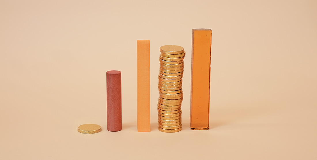bars and stacks of gold coins on beige background