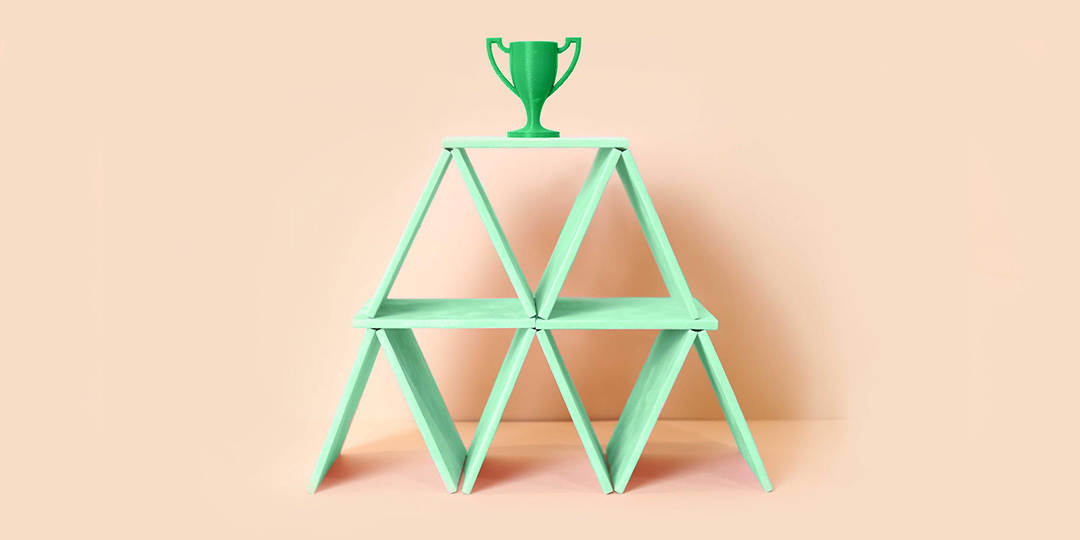 Green trophy on top of green card pyramid