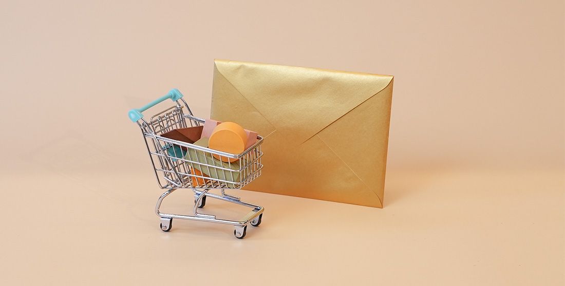 Small shopping cart in front of gold envelope